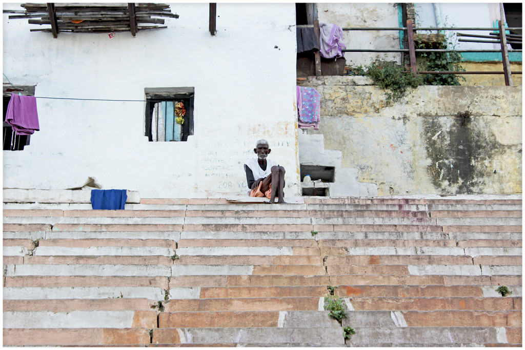 Man sitting on the steps next to the river Ganga.